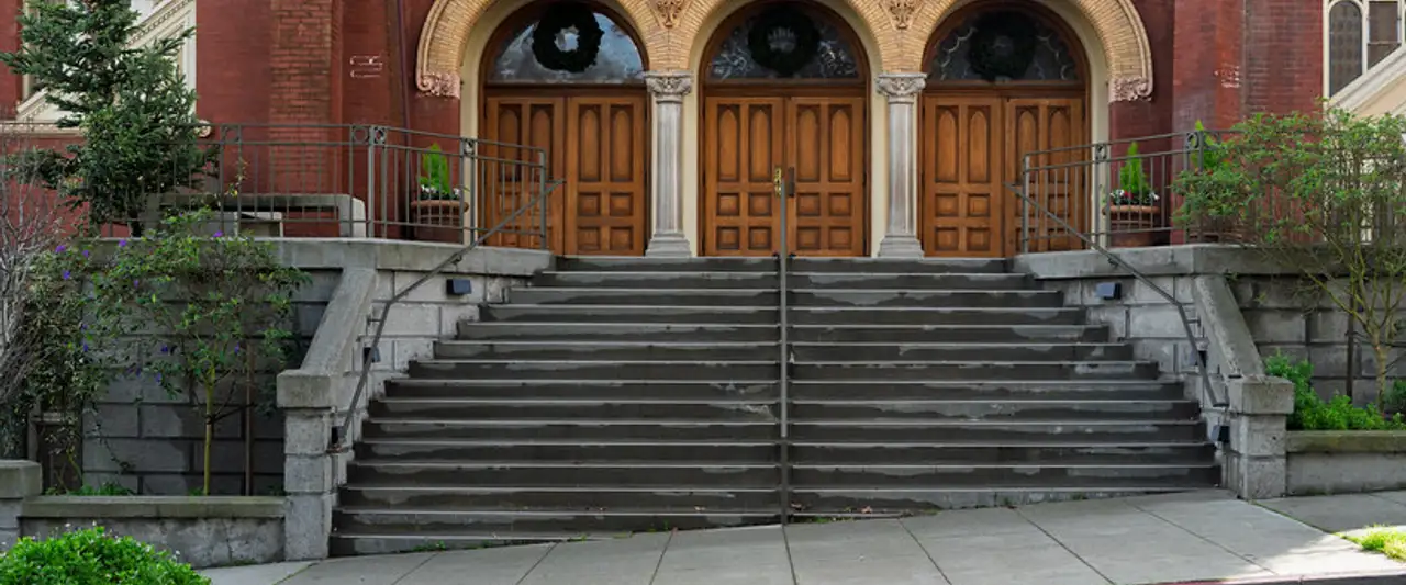 Open arched doors at the top of the steps of a red-brick church